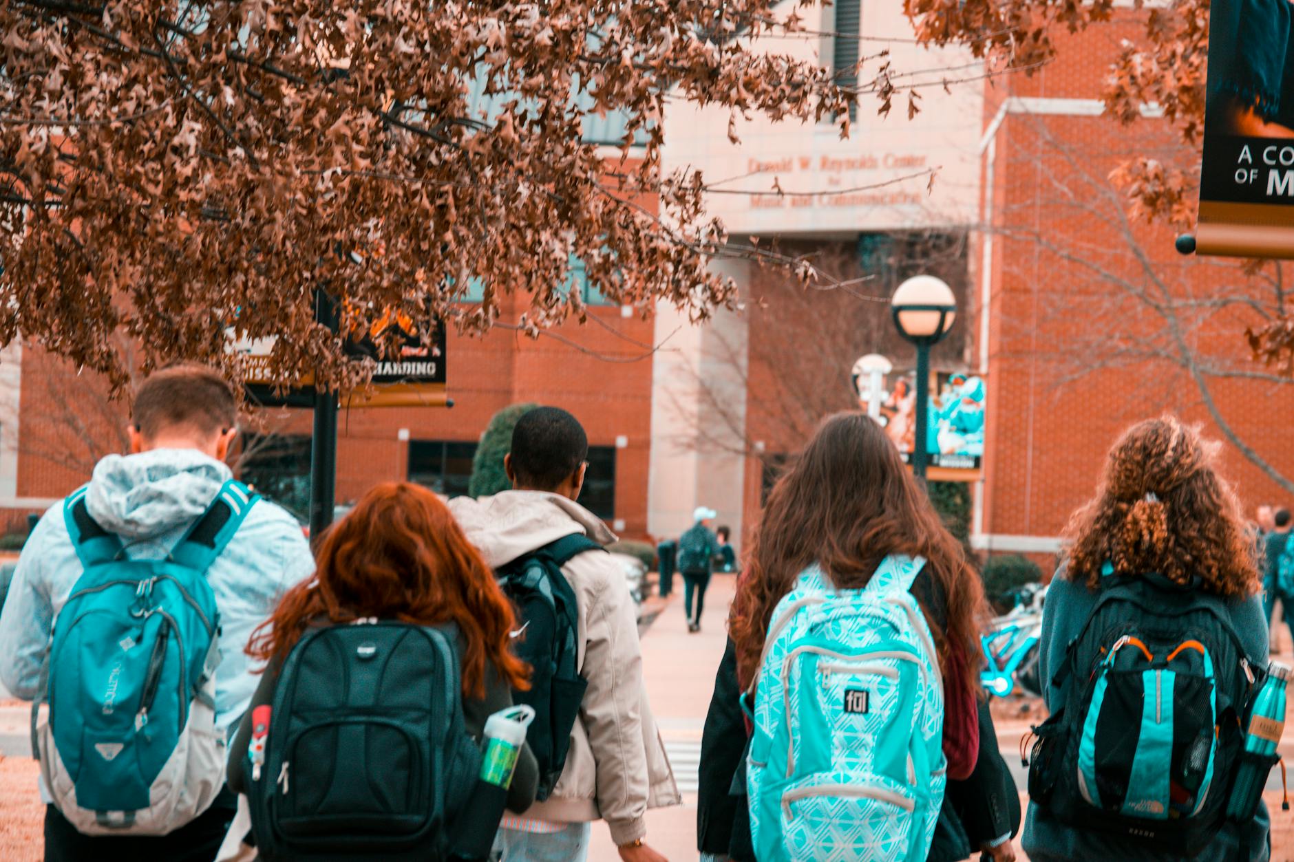 Students walking across university campus quad with academic buildings in background
