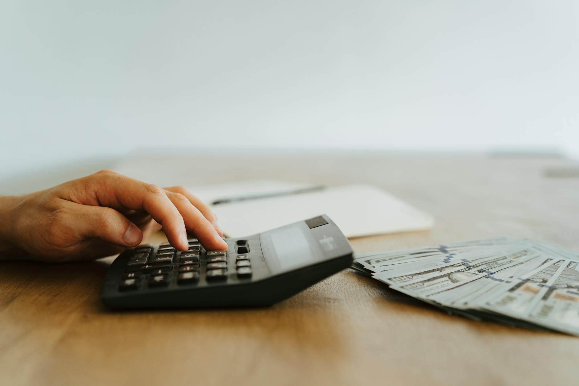 Calculator surrounded by dollar bills showing cost calculations and financial planning