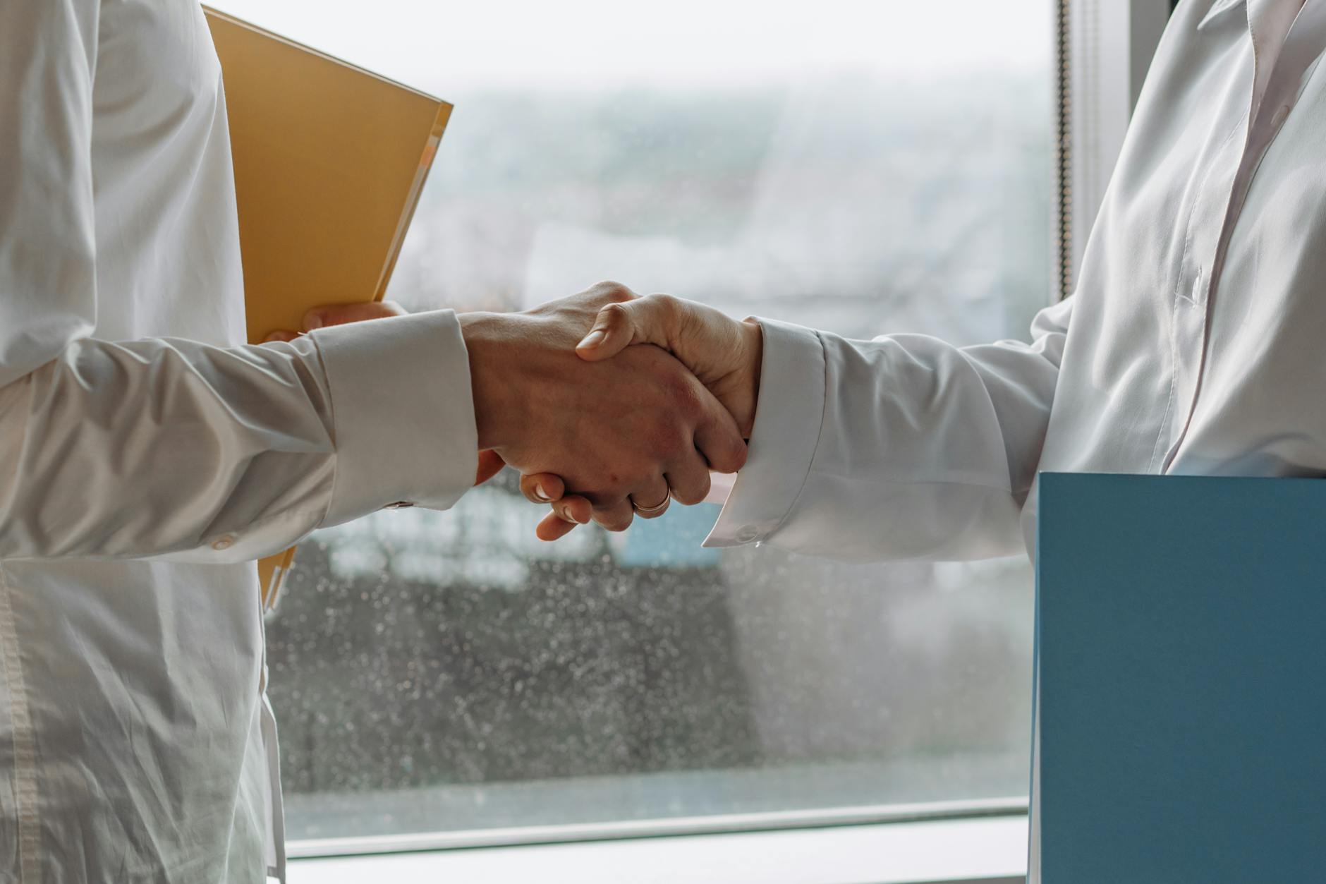 Professional handshake representing partnership between employers and employees through equity ownership