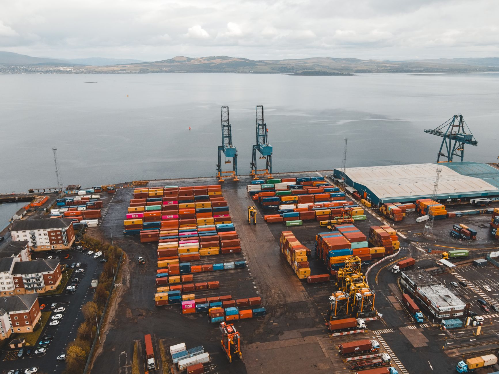Aerial view of a large container seaport with stacked shipping containers and cranes