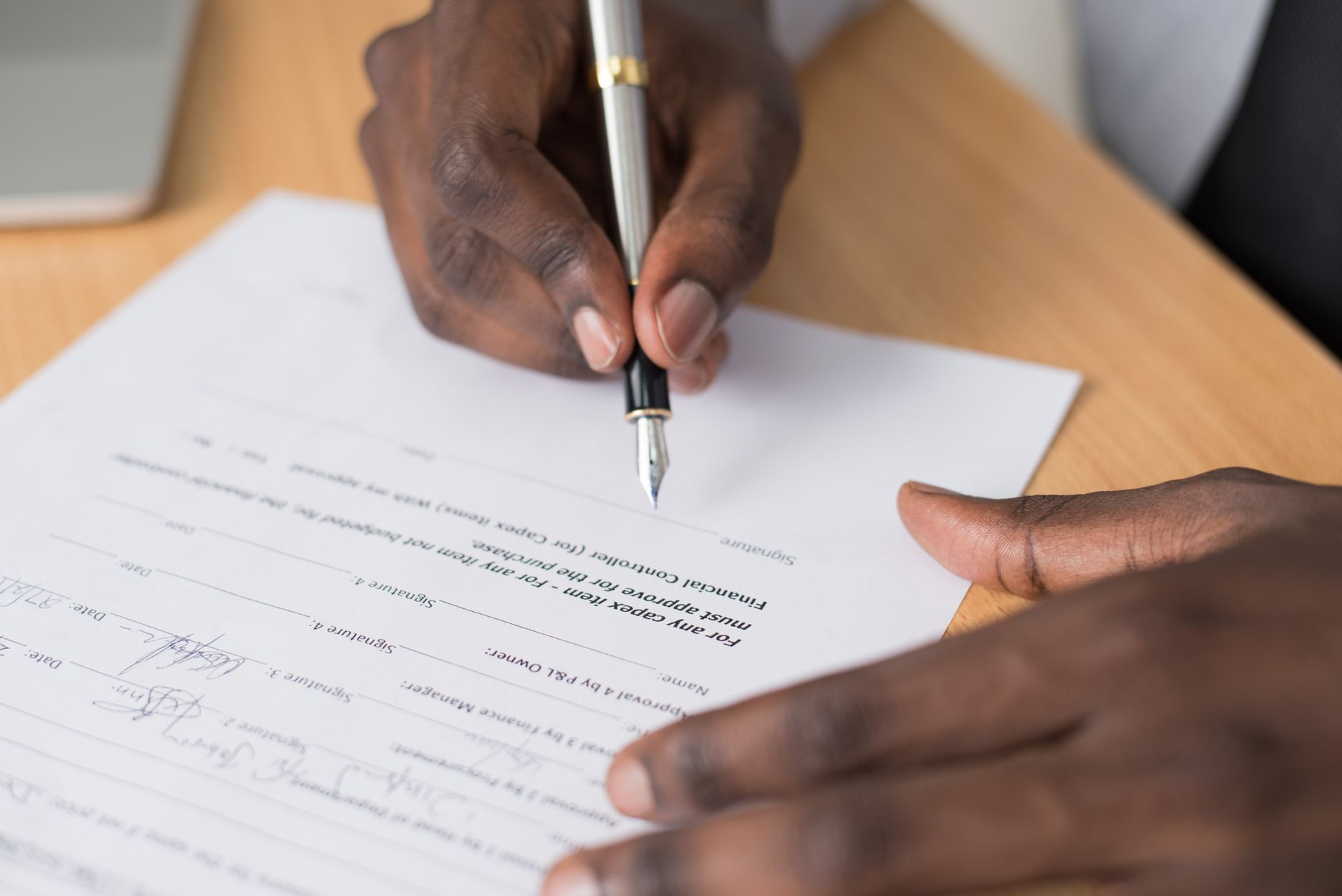 Two professionals reviewing and signing a legal contract at a desk
