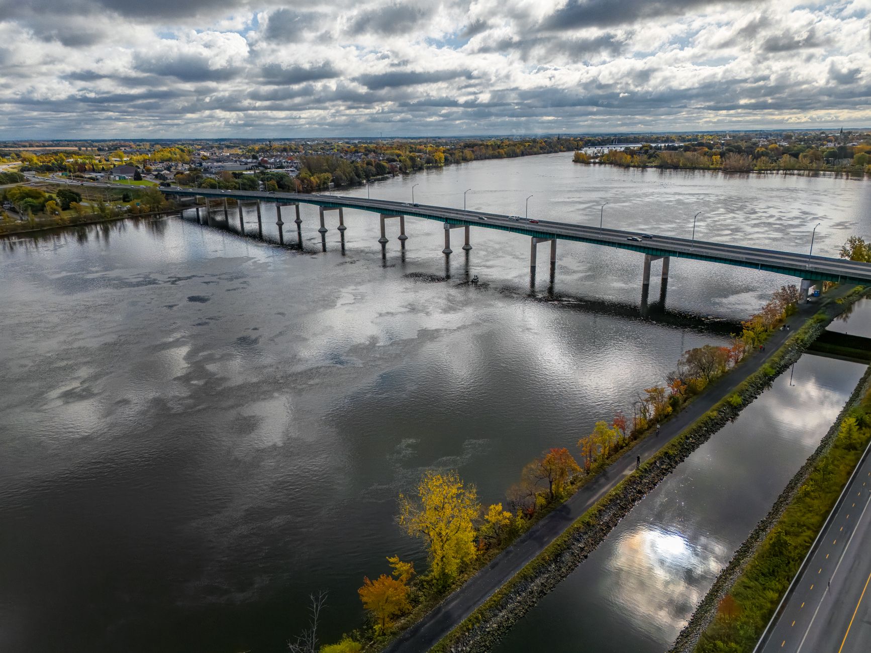Aerial view of a toll bridge spanning a wide river in an urban corridor