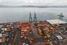 Aerial view of a large commercial seaport with container ships and loading cranes