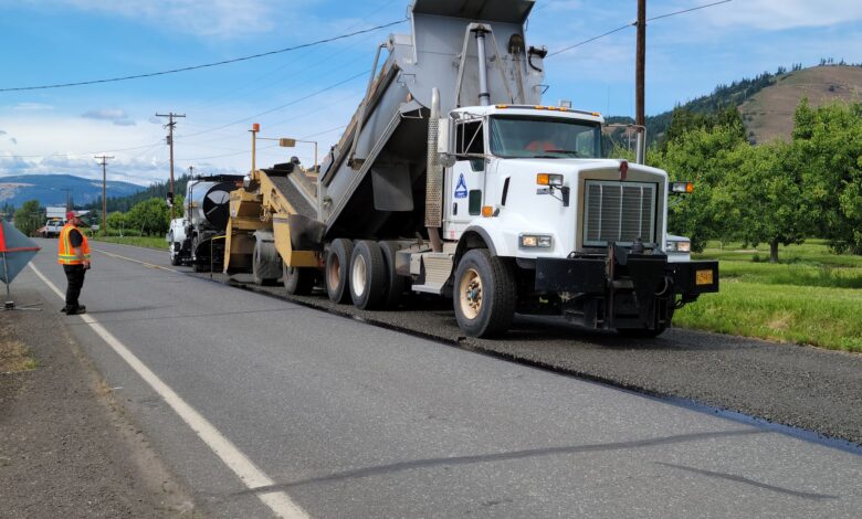 Road construction workers laying fresh liquid asphalt on a highway surface