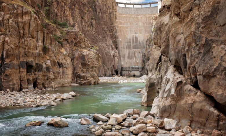Large hydropower dam with water flowing through spillways in a mountain river valley