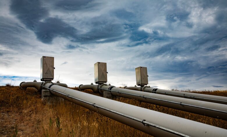 A natural gas pipeline running across open rural farmland under a wide sky