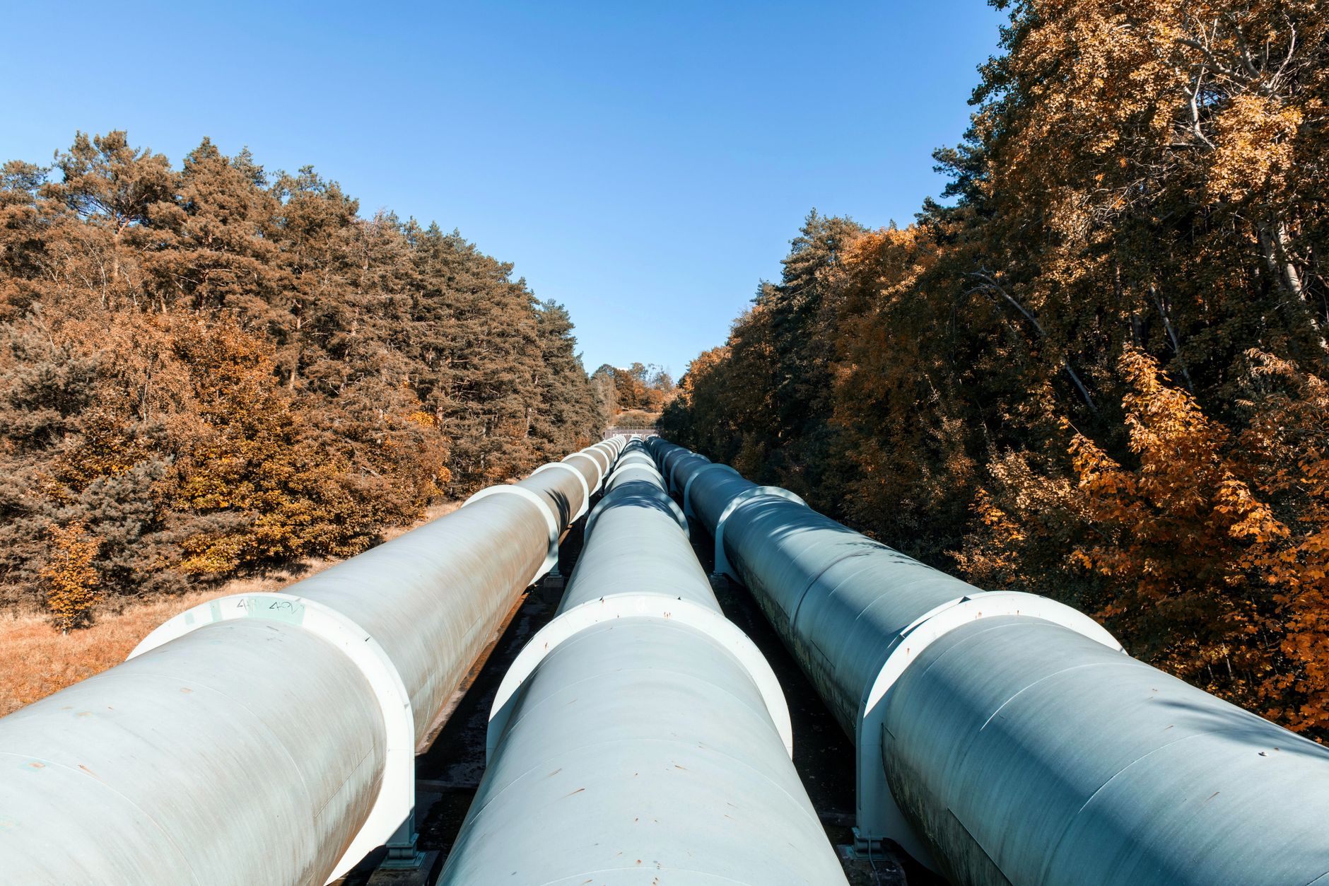 Industrial pipeline infrastructure stretching across open land near an industrial facility