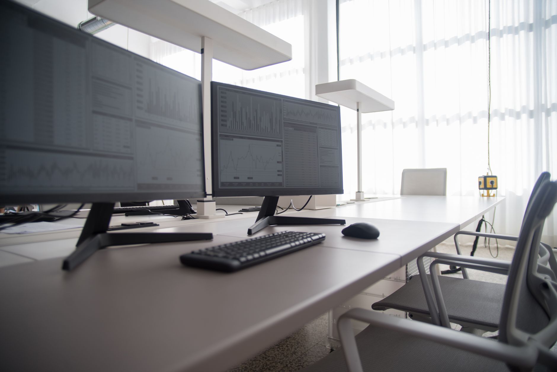 Interior of a financial trading office with multiple screens displaying market data