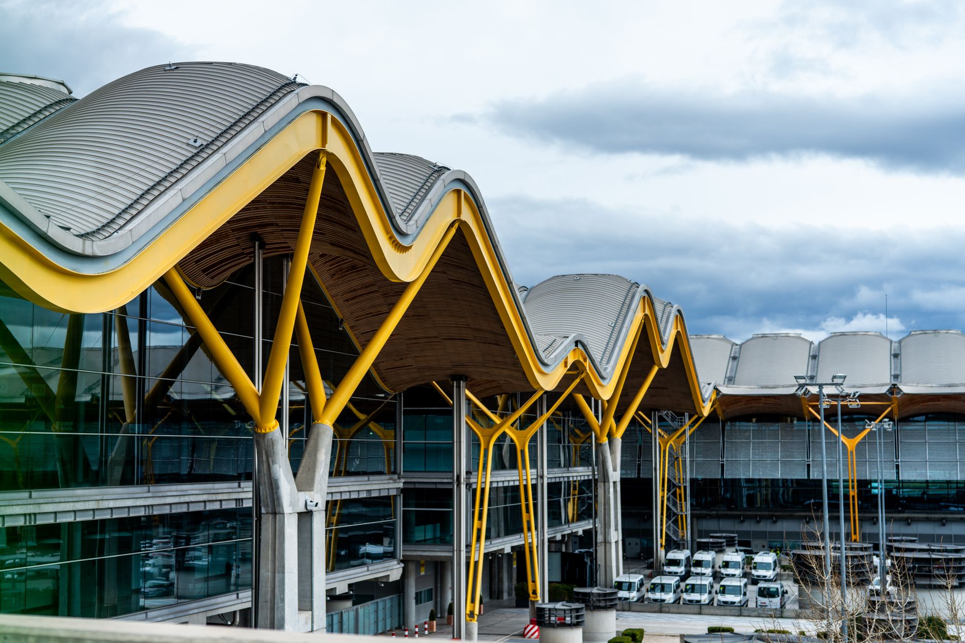 Wide exterior view of a busy commercial airport terminal with vehicle access road
