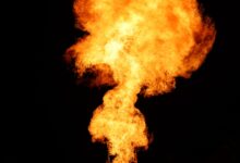 Gas flare burning at an oil production site at dusk
